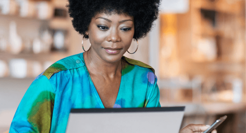 Woman working on notebook and holding cellphone