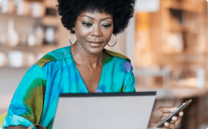 Woman holding a cellphone and looking at notebook