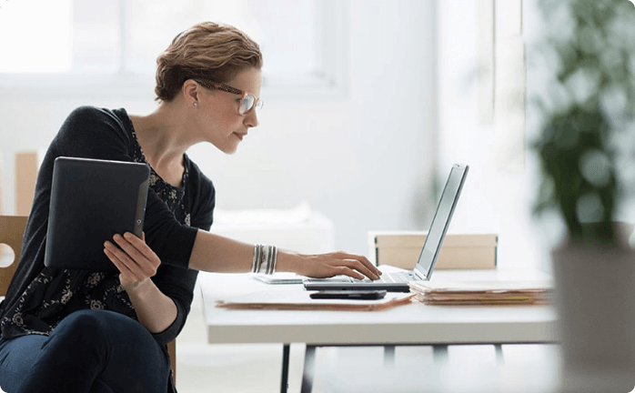 Woman looking at notebook and holding a tablet
